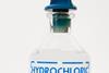 A close-up image of a glass bottle of dilute hydrochloric acid with a blue stopper