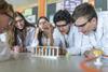 A group of A-level students doing a practical experiment, boy using a pipette to add to a test tube.