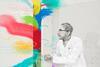 An illustration of a man in a lab coat opening a door with colours flooding in