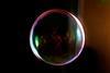 A close-up enhanced image of a soap bubble against a black background
