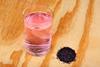 Crystals of potassium permanganate(VII) and a glass of water with a pink-purple hue on a wooden surface