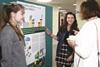 Three people gathered round a scientific poster
