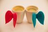 An image showing two cups of coffee with Cupid wings on them