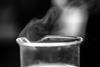 A photograph of a glass beaker containing a liquid, with a gas visibly rising from the top