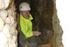 Tom is inside a cave wearing a protective helmet. 