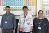 Three people standing in front of a periodic table
