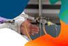 The hand of a teacher in a lab coat gestures towards a Liebig condenser used for distillation