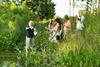 A teacher showing students some science by a wildlife pond