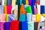 Bolts of colourful cloth on sale at local fabric market store.