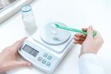 An image of a person weighing out a reagent on a balance scale
