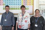 Three people standing in front of a periodic table