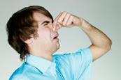 A man holding his nose with a disgusted expression