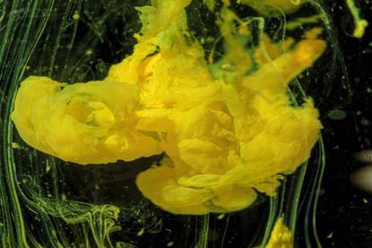 A yellow precipitate forming in a clear liquid against a black background