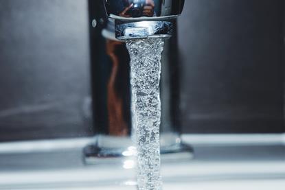 A close-up photograph of water flowing from a silver tap