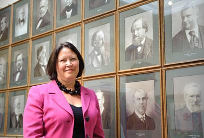 Professor Yellowlees standing in front of past portraits of RSC Presidents