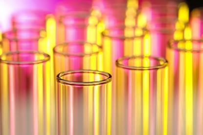 A close-up photograph of the tops of glass test tubes in a laboratory