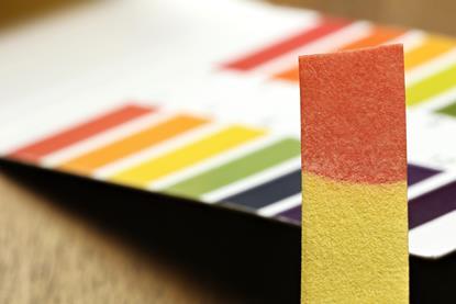 Universal indicator strip coloured red, with colour identification chart in the background