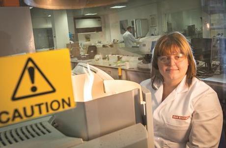 Nicola looking at a test tube with a florescent liquid in