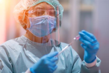 Photo of lab technician scientist in PPE holding vaccine test