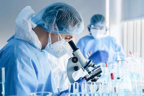 Photo of a laboratory scientist looking into a microscope