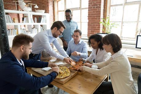 Group of colleagues tucking into pizzas together